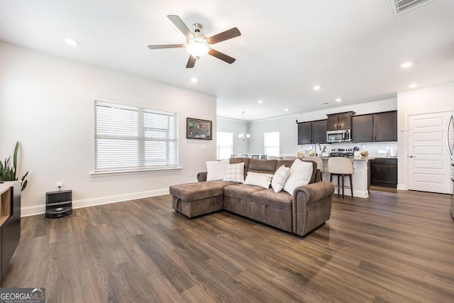 living room featuring dark wood-type flooring, baseboards, a ceiling fan, and visible vents