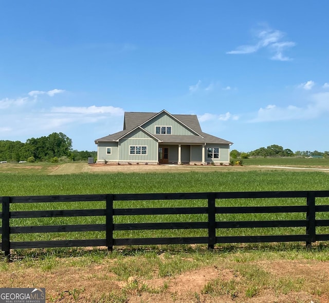 view of front facade with a front lawn, board and batten siding, and fence