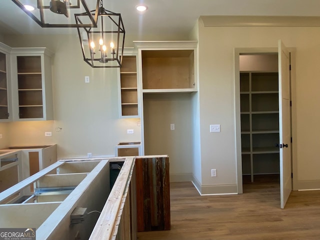 kitchen with an inviting chandelier, pendant lighting, wood finished floors, baseboards, and recessed lighting