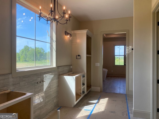 bathroom featuring an inviting chandelier and tile walls
