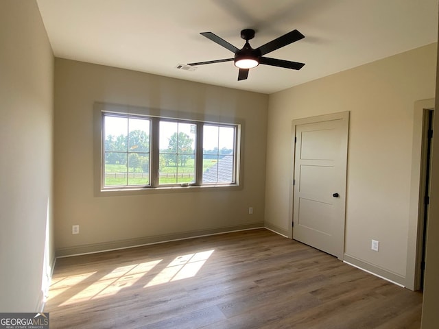 unfurnished bedroom featuring visible vents, baseboards, ceiling fan, and wood finished floors