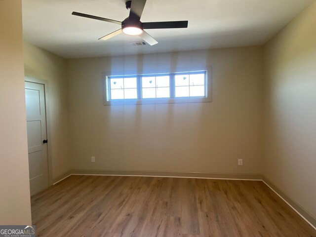spare room featuring baseboards, ceiling fan, wood finished floors, and visible vents