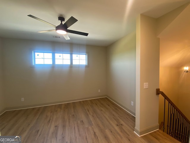 empty room featuring visible vents, a ceiling fan, baseboards, and wood finished floors
