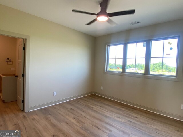 empty room with a ceiling fan, baseboards, visible vents, and light wood-type flooring