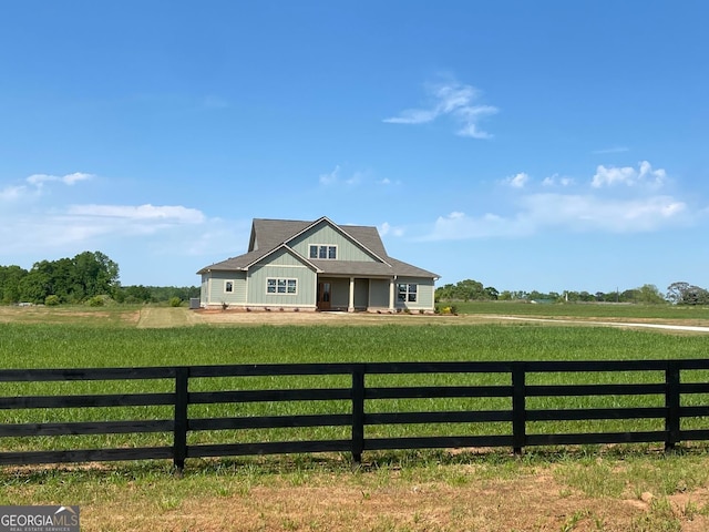 view of front of home featuring a rural view, board and batten siding, fence, and a front yard