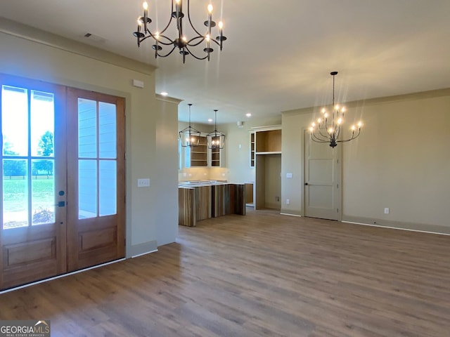 interior space featuring an inviting chandelier, baseboards, wood finished floors, and french doors