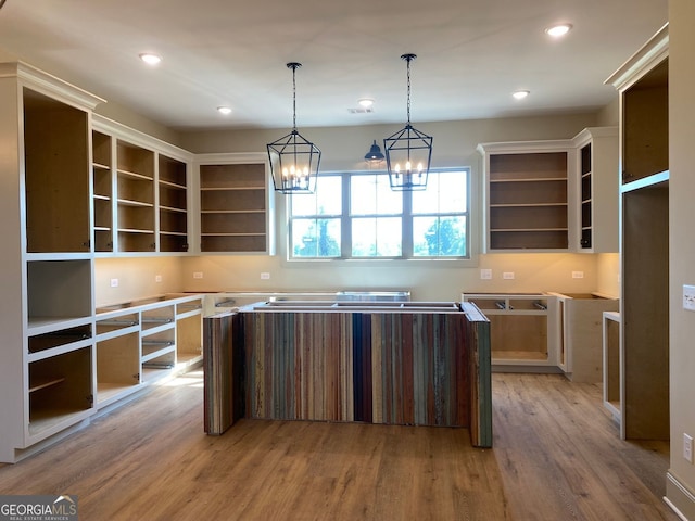 kitchen with open shelves, light wood-style flooring, a notable chandelier, and decorative light fixtures