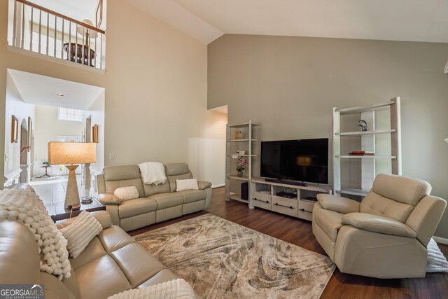 living area with baseboards, high vaulted ceiling, and wood finished floors