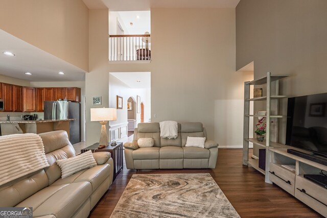 living area featuring recessed lighting, dark wood-style flooring, and a towering ceiling