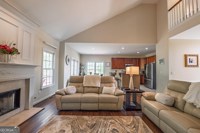 living room with a high end fireplace, dark wood finished floors, baseboards, high vaulted ceiling, and recessed lighting