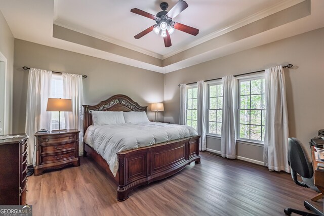bedroom with crown molding, a raised ceiling, baseboards, and wood finished floors