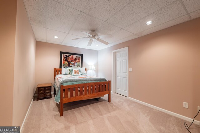 carpeted bedroom with baseboards, a drop ceiling, and ceiling fan