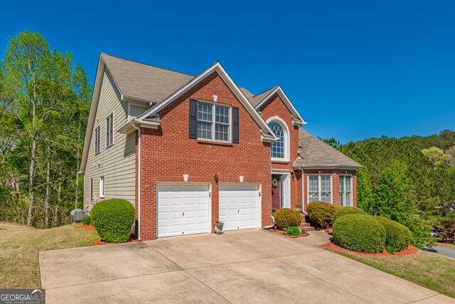 traditional-style home featuring concrete driveway, brick siding, and a garage