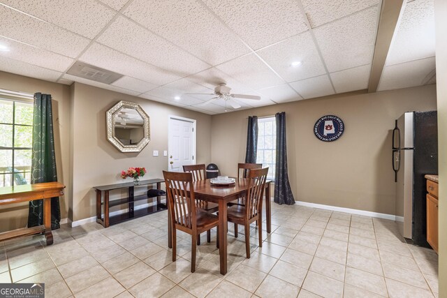 dining space featuring a ceiling fan, a drop ceiling, and light tile patterned floors
