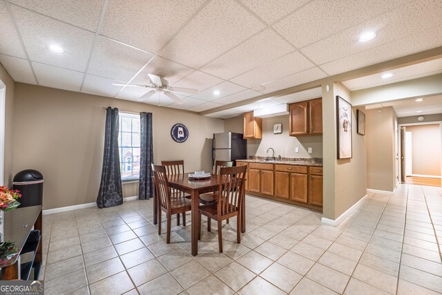dining space with a paneled ceiling, baseboards, ceiling fan, and light tile patterned floors