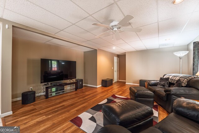 living room featuring baseboards, ceiling fan, a drop ceiling, and wood finished floors
