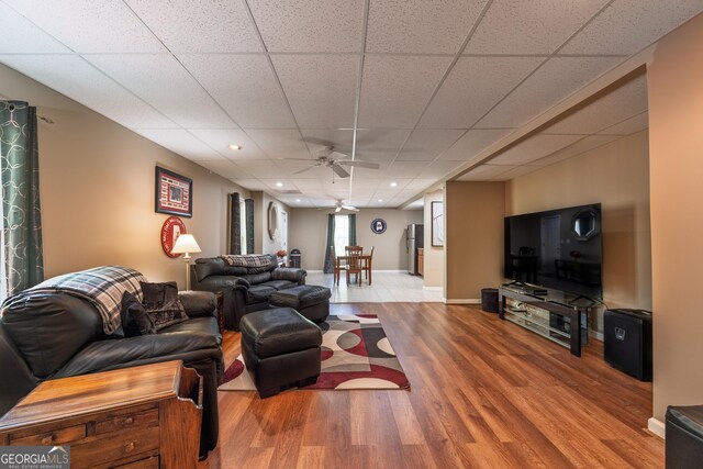 living room with wood finished floors, baseboards, ceiling fan, recessed lighting, and a paneled ceiling