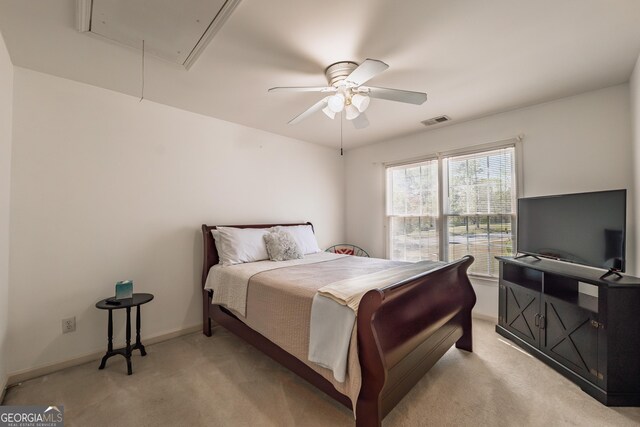 bedroom with a ceiling fan, attic access, visible vents, light colored carpet, and baseboards