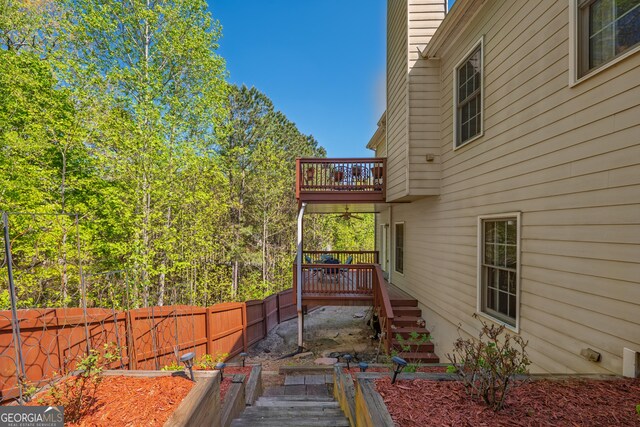 view of side of property featuring a wooden deck, fence, a balcony, a chimney, and stairway