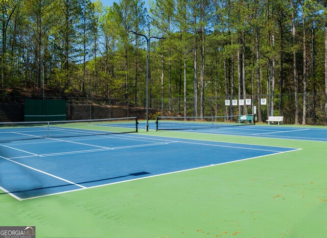 view of sport court with fence, community basketball court, and a forest view