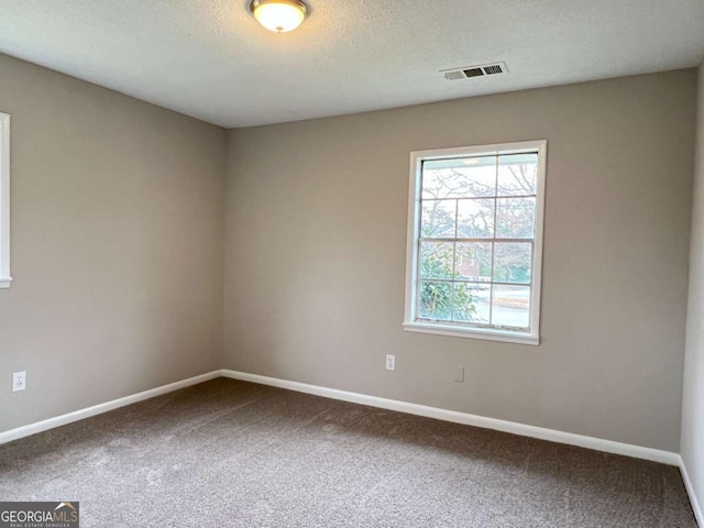 carpeted spare room featuring baseboards, a textured ceiling, and visible vents