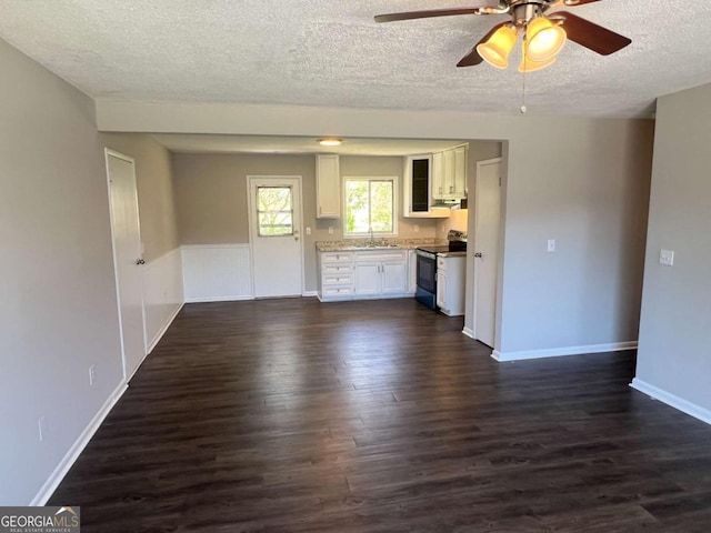 interior space with baseboards, a textured ceiling, a ceiling fan, and dark wood finished floors