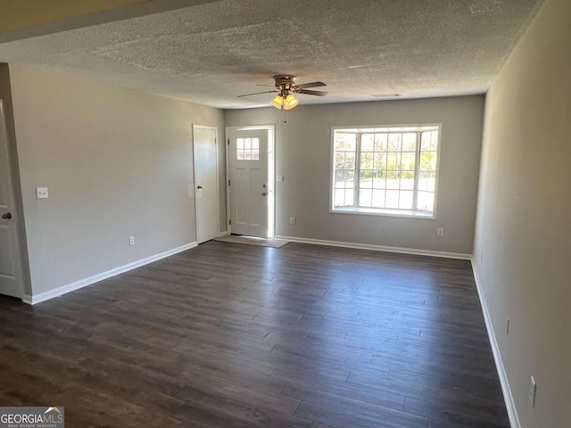 unfurnished living room featuring a ceiling fan, dark wood-style floors, and baseboards
