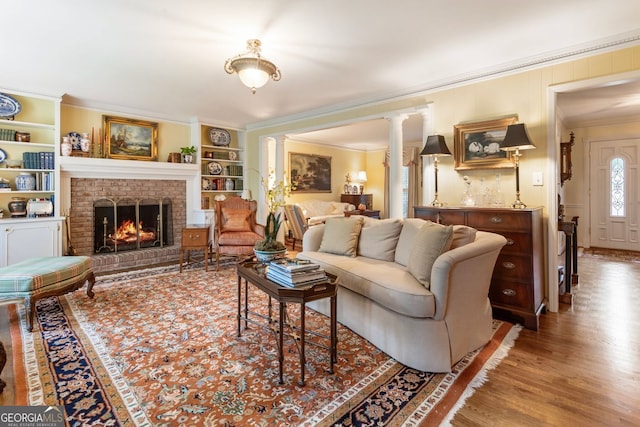 812 Burning Tree Ct SE, Marietta, GA 30067 - living area with crown molding, decorative columns, wood finished floors, a brick fireplace, and built in shelves