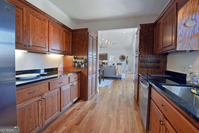 47 Hidden Fields Rd, Hiawassee, GA 30546 - kitchen with dark stone counters, brown cabinetry, light wood-style floors, appliances with stainless steel finishes, and a notable chandelier