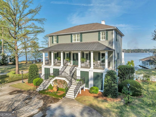 view of front of home with a chimney, a water view, a porch, and stairway