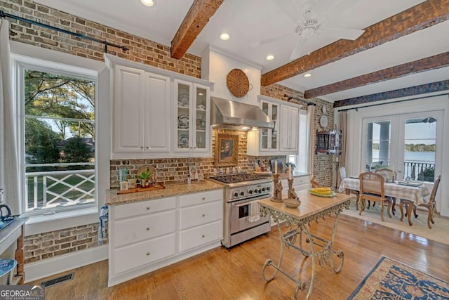 kitchen featuring wall chimney range hood, visible vents, plenty of natural light, and stainless steel stove