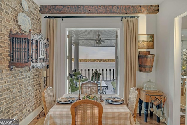 dining area with a water view, brick wall, and a ceiling fan