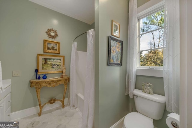 bathroom with toilet, baseboards, and a wealth of natural light