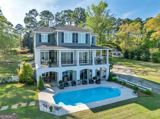 back of house featuring a balcony, a lawn, an outdoor living space, and a patio