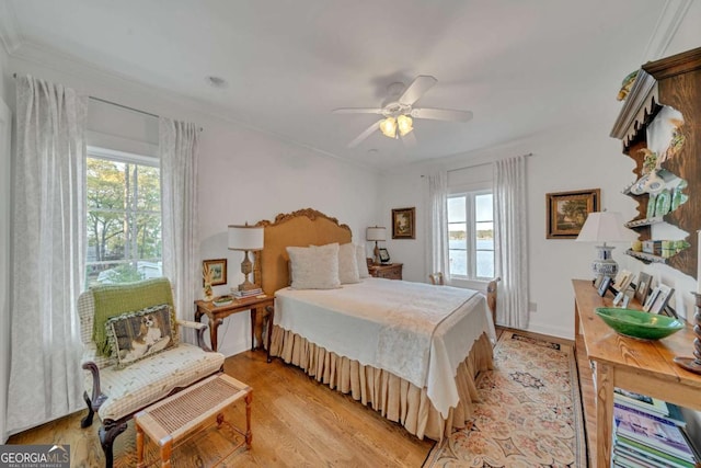 bedroom with multiple windows, a ceiling fan, baseboards, and light wood-style floors