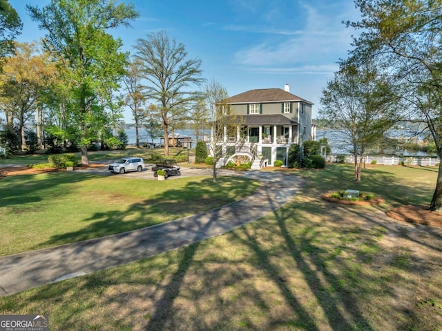 view of front facade featuring covered porch, a chimney, stairs, and a front lawn