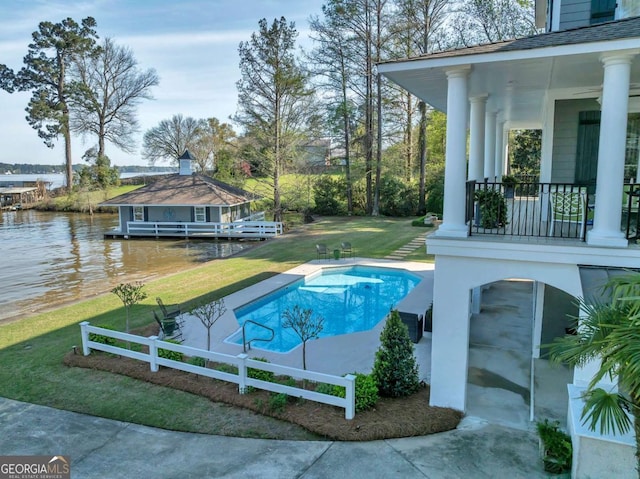 outdoor pool featuring fence, a water view, and a yard