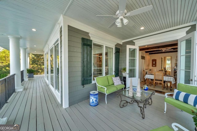 wooden terrace with outdoor lounge area, covered porch, and a ceiling fan