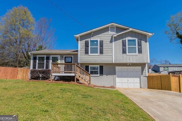 tri-level home with stairway, fence, driveway, a front yard, and a garage