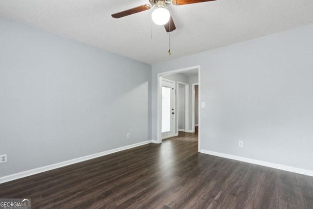 empty room featuring baseboards, ceiling fan, and dark wood-style flooring