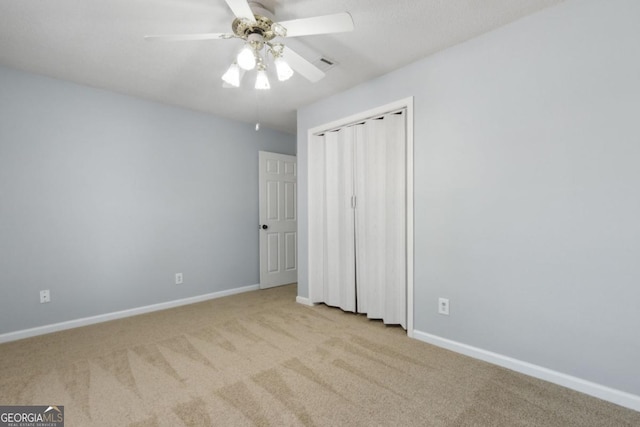 unfurnished bedroom with a closet, carpet flooring, baseboards, visible vents, and ceiling fan