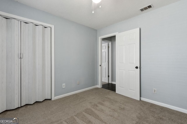 unfurnished bedroom with carpet flooring, baseboards, ceiling fan, visible vents, and a closet