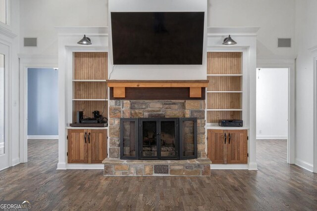 unfurnished living room featuring baseboards, a fireplace, visible vents, and wood finished floors