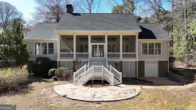 rear view of house with a shingled roof, a sunroom, a garage, and stairway