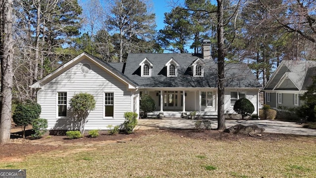 cape cod-style house with a front lawn, a chimney, and entry steps