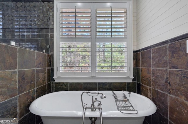 bathroom featuring a freestanding tub and tile walls