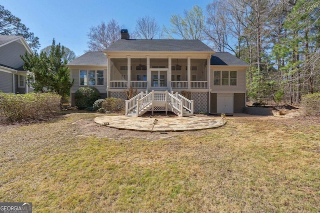 rear view of property featuring a yard, a sunroom, stairs, and a chimney