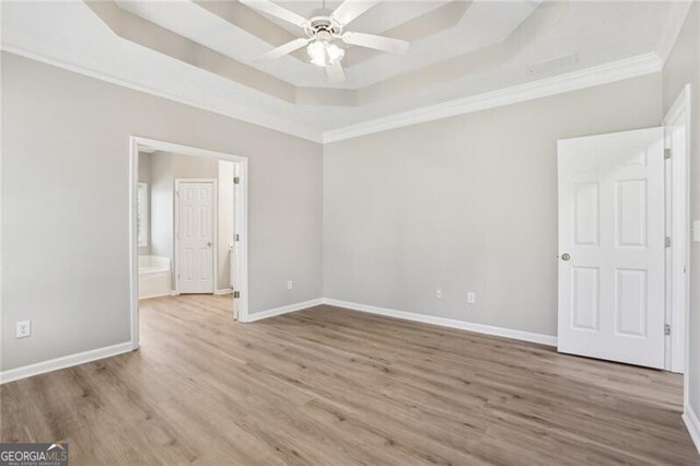 unfurnished bedroom with crown molding, wood finished floors, and a raised ceiling