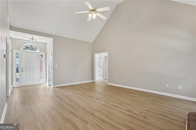 unfurnished living room with high vaulted ceiling, baseboards, and light wood-type flooring