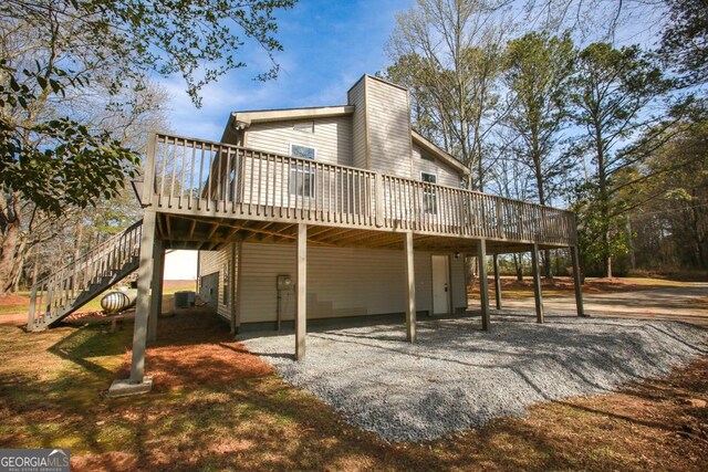 759 Oak Grove Rd, Carrollton, GA 30117 - back of property with gravel driveway, a deck, a chimney, and a carport